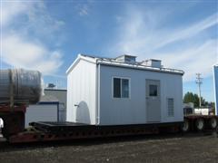 A prefabricated equipment building loaded on a flatbed trailer.